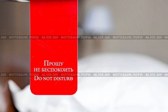 A hotel room with a red sign that says "Please do not disturb." The concept of a hotel stay. Стоковое фото, фотограф Photojuli / Фотобанк Лори