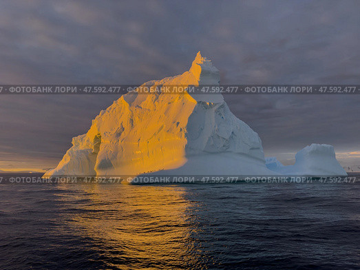 A huge high breakaway glacier drifts in the southern ocean off the coast of Antarctica at sunset, the Antarctic Peninsula, the Southern Arctic Circle, azure water, cloudy weather. Стоковое фото, фотограф Vladimir Drozdin / Фотобанк Лори