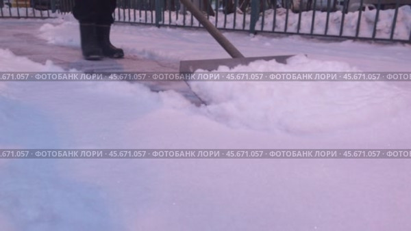 A janitor collects freshly fallen snow with a shovel in the yard. Close up. Стоковое видео, видеограф Ярославский Максим / Фотобанк Лори
