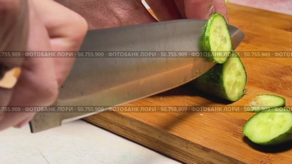 A knife is cutting a cucumber on a wooden cutting board. Стоковое видео, видеограф Ярославский Максим / Фотобанк Лори
