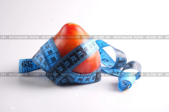 A large red tomato is wrapped with a measuring tape on a white background. Стоковое фото, фотограф Ярославский Максим / Фотобанк Лори