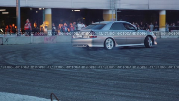 A large silver drift car burns rubber for the amusement of the audience with smoke at the demonstration performances at the Mega Belaya Dacha site. Slow motion. Russia. Moscow. 19.05.2024. Стоковое видео, видеограф Ярославский Максим / Фотобанк Лори