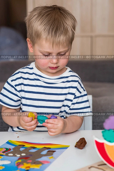 A little boy is playing with plasticine. Fine motor skills-developing games for children. The kid makes a horse. Useful games for child development. Стоковое фото, фотограф Photojuli / Фотобанк Лори