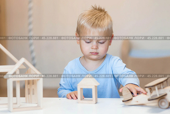 A little boy of 2 years old is playing a developing logistics constructor. Children's wooden toys. Montessori for child development. Стоковое фото, фотограф Photojuli / Фотобанк Лори