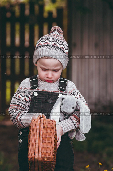 A little boy of 4 years old outdoors with a suitcase and a stuffed rabbit goes on a journey. A beautiful portrait of a child playing on the street. Стоковое фото, фотограф Photojuli / Фотобанк Лори