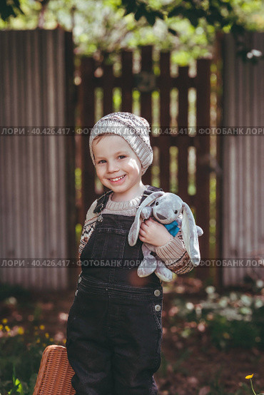 A little boy of 4 years old outdoors with a suitcase and a stuffed rabbit goes on a journey. A beautiful portrait of a child playing on the street. Стоковое фото, фотограф Photojuli / Фотобанк Лори