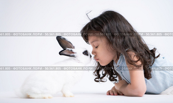 A little girl kisses her beloved fluffy rabbit, The beauty of friendship between humans and animals. Стоковое фото, агентство Ingram Publishing / Фотобанк Лори