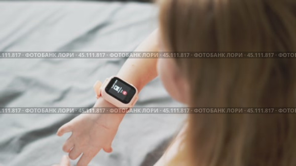 A little girl wears a smartwatch on her wrist and controls the functions by tapping on the screen. Стоковое видео, видеограф Енваев Андрей / Фотобанк Лори
