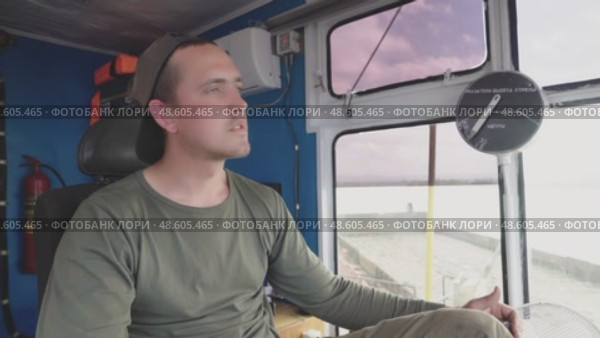 A male crane operator demonstrates his expertise as he navigates the crane's joystick with precision and focus. He is seated in the cabin, clearly engaged in his task as he operates heavy machinery. Стоковое видео, видеограф Владимир Разгуляев / Фотобанк Лори