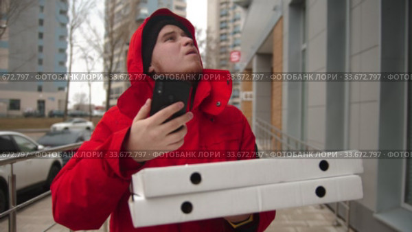 A man courier delivering pizza - walking on the street and looking at the phone. Стоковое видео, видеограф Константин Шишкин / Фотобанк Лори