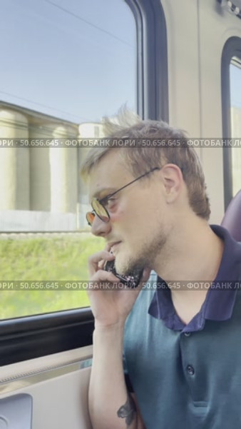 A man in dark glasses and a green shirt is sitting on a train. Стоковое видео, видеограф Ярославский Максим / Фотобанк Лори