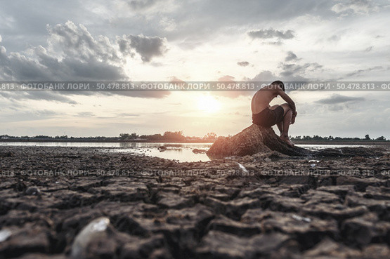 A man sat bent his knees on the base of the tree where the floor was dry and hands placed on the head. Стоковое фото, агентство Ingram Publishing / Фотобанк Лори