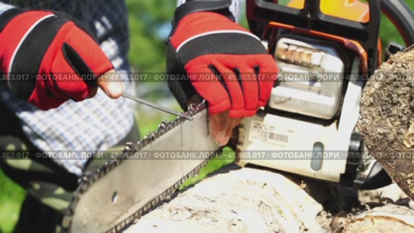 A man sharpens a chain at a chainsaw in the garden. Стоковое видео, видеограф Igor Skripachev / Фотобанк Лори