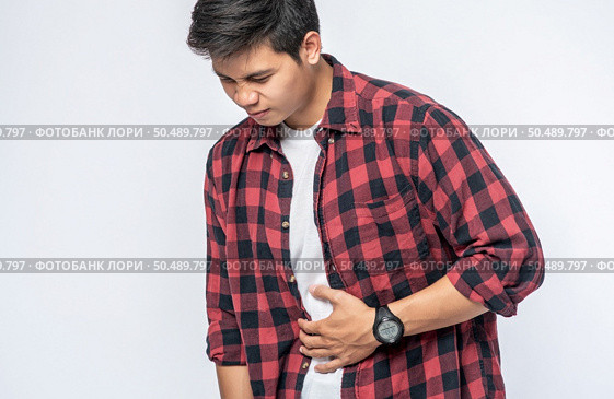 A man stands with a stomachache and puts his hand on his stomach. Стоковое фото, агентство Ingram Publishing / Фотобанк Лори
