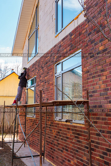 A man works with a drill, attaches thermal panels made of clinker. Стоковое фото, фотограф Юрий Поздников / Фотобанк Лори