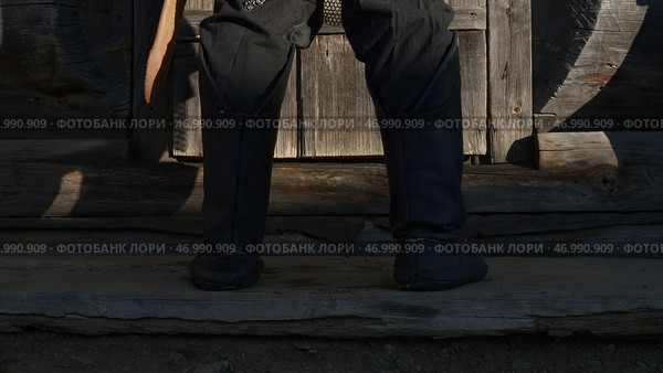 A medieval warrior legs in ancient shoes against wooden house doorstep. Стоковое фото, фотограф David Kashakhi / Фотобанк Лори