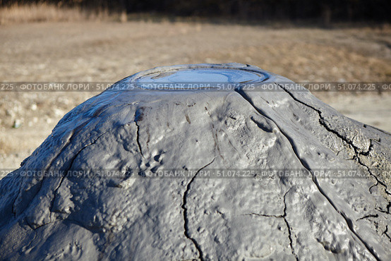 A mud volcano and a stream of grey clay from an eruption and gas escape. Cracked soil surface. Texture of a mudflow. Стоковое фото, фотограф Наталия Кирсанова / Фотобанк Лори