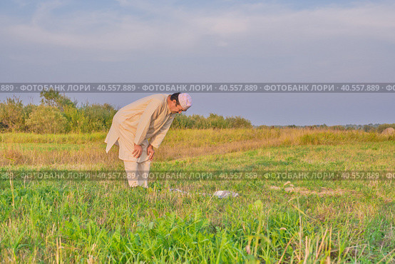 A Muslim senior man wearing an embroidered skullcap and white traditional clothes prays. Стоковое фото, фотограф Ирина Кононова / Фотобанк Лори
