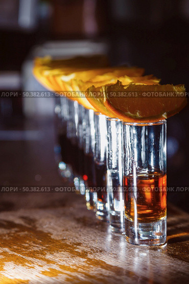 A number of shots with golden tequila and orange slices. Close-up. Стоковое фото, агентство Ingram Publishing / Фотобанк Лори
