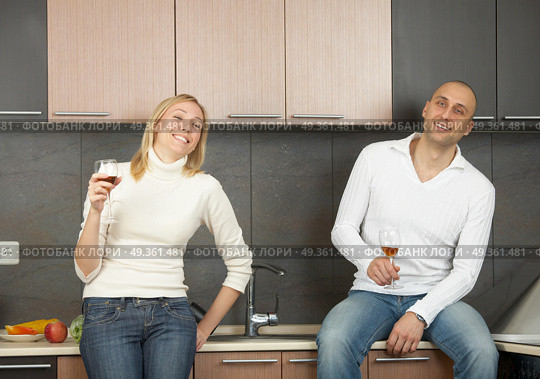 A pair laughs and drinks wine on a kitchen. Pair with wine. Стоковое фото, агентство Ingram Publishing / Фотобанк Лори
