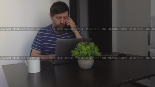A person working at home on a laptop answers a phone call. Стоковое видео, видеограф Ярославский Максим / Фотобанк Лори