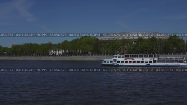 A pleasure boat passes along the Moscow River past a large sports arena. It's a sunny day. Russia. Moscow. 01.05.2024. Редакционное видео, видеограф Ярославский Максим / Фотобанк Лори