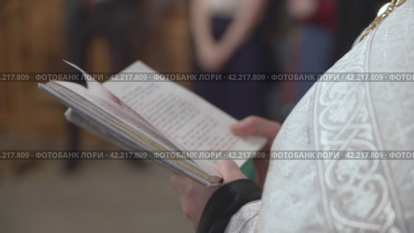 A priest holds a Bible in his hands. Стоковое видео, видеограф Потийко Сергей / Фотобанк Лори