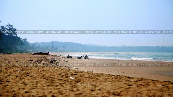 A Serene Beach Landscape featuring Gentle Waves lapping against the shore and Distant Hills beyond. Стоковое фото, фотограф David Kashakhi / Фотобанк Лори
