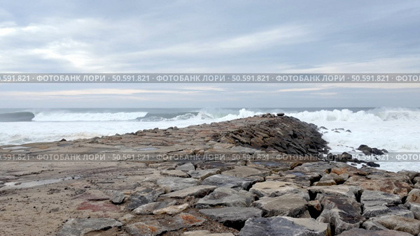 A stone jetty stretches into the turbulent ocean at Furadouro, Portugal, a location renowned for its challenging surf conditions that attract international competitions. Стоковое фото, агентство Ingram Publishing / Фотобанк Лори