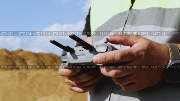 a surveyor on a construction site controls a quadcopter. Стоковое видео, видеограф Igor Skripachev / Фотобанк Лори