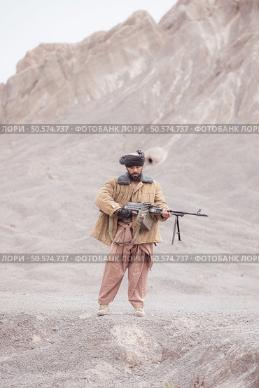 A Taliban soldier stands with a machine gun, In the desert mountain landscape. Стоковое фото, агентство Ingram Publishing / Фотобанк Лори