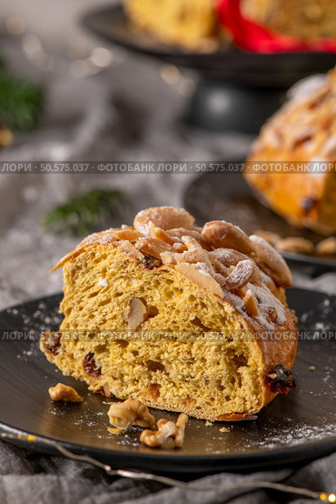 A tempting slice of Bolo Rainha, a traditional Portuguese Christmas cake, is presented on a black plate. It’s topped with almonds and dusted with powdered sugar. Стоковое фото, агентство Ingram Publishing / Фотобанк Лори