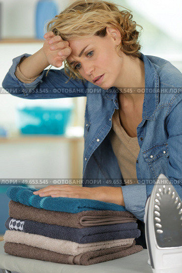 a tired woman ironing towels. Стоковое фото, агентство Ingram Publishing / Фотобанк Лори
