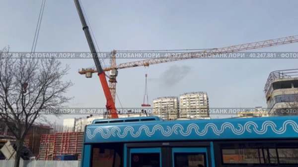 A tower crane moves cargo on a construction site. Construction of a shopping complex in a residential area. Стоковое видео, видеограф Ярославский Максим / Фотобанк Лори