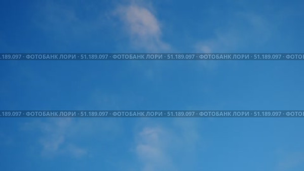 A tranquil blue sky adorned with soft, fluffy clouds creates a serene atmosphere. The gentle movement of the clouds invites viewers to pause and appreciate nature beauty on this lovely day. Стоковое видео, видеограф Юлия Петровская / Фотобанк Лори