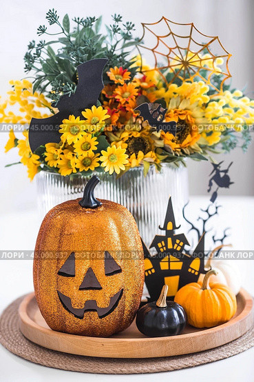 A vase of flowers, pumpkins and a scary castle with a witch on the background of a Scandi-style white kitchen interior. The concept of home and comfort. Autumn decor for Halloween. Стоковое фото, фотограф Photojuli / Фотобанк Лори