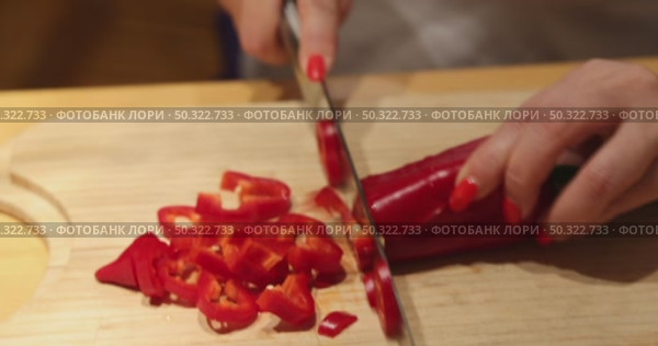 A visually satisfying close-up video of a woman’s hands with elegant manicured nails precisely slicing fresh red bell peppers on a cutting board. Ideal for cooking tutorials and lifestyle content. Стоковое видео, видеограф Виктор Ветошкин / Фотобанк Лори