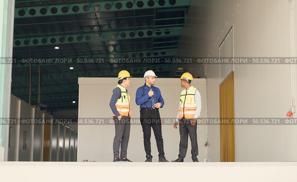 A warehouse manager and two employees are resting after dealing with how to organize the shelves in a large warehouse. Стоковое фото, агентство Ingram Publishing / Фотобанк Лори