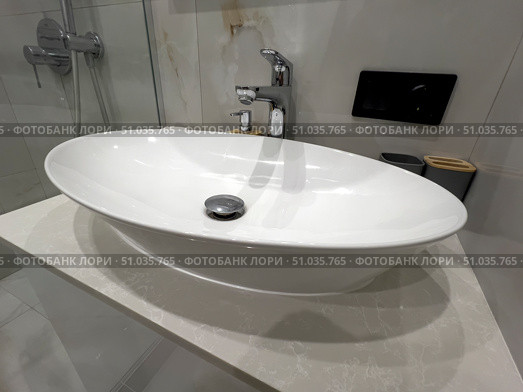 A white porcelain sink with a chrome faucet sits on a white countertop. Стоковое фото, фотограф Ярославский Максим / Фотобанк Лори
