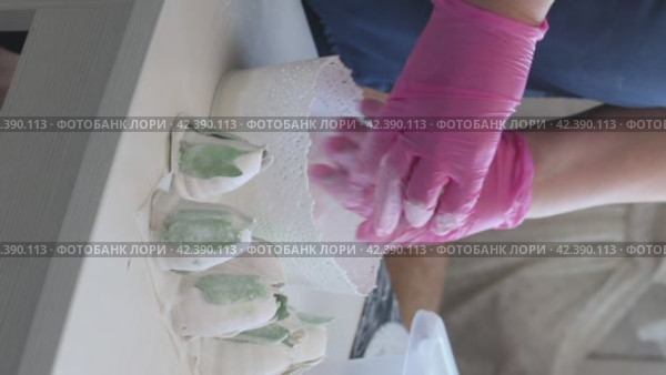 A woman covers a homemade marshmallow with powdered sugar. Tulip buds made of marshmallows with green leaves. Vertical video. Стоковое видео, видеограф Vadzim Yakubovich / Фотобанк Лори