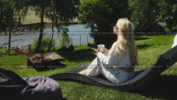 A woman enjoys a serene day in nature, relaxing with her phone. Стоковое видео, видеограф Cantemir Dumitru / Фотобанк Лори