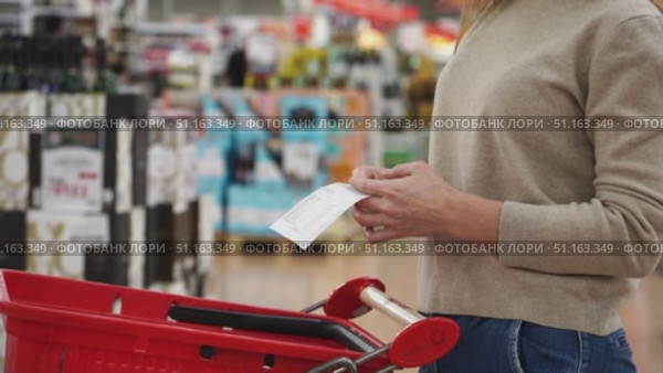 A woman in a supermarket looks at a receipt from purchases. Стоковое видео, видеограф Igor Skripachev / Фотобанк Лори