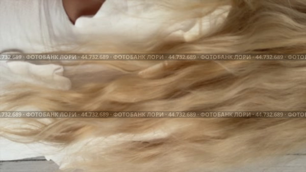 A woman is showcasing her curls. She created them using a curling wand, hair styler. Vertical video. Стоковое видео, видеограф Vadzim Yakubovich / Фотобанк Лори