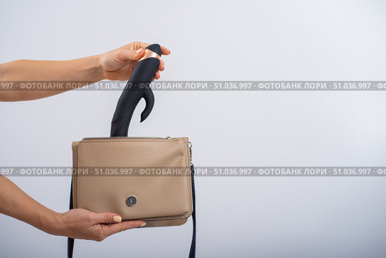 A woman puts a dildo in a handbag on a white background. Close-up of female hands with a black vibrator. Стоковое фото, фотограф Михаил Решетников / Фотобанк Лори