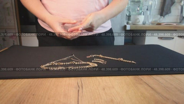 A woman reviewing jewelry, laying out a gold-colored necklace, bracelet, earrings, and ring on a table. Стоковое видео, видеограф Vadzim Yakubovich / Фотобанк Лори