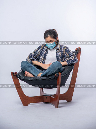 A woman sitting in a chair with abdominal pain and pressing her hand on her stomach. Стоковое фото, агентство Ingram Publishing / Фотобанк Лори