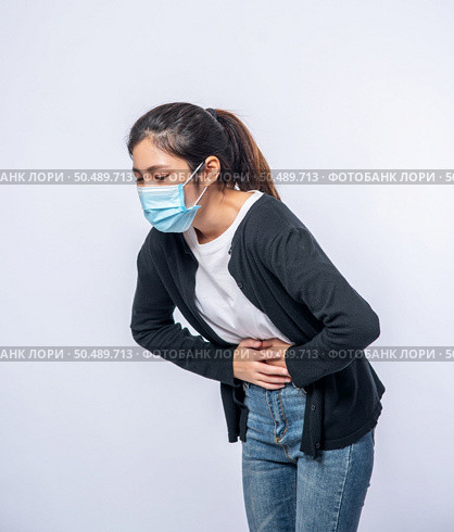 A woman standing with a stomach ache and presses her hand on her stomach. Стоковое фото, агентство Ingram Publishing / Фотобанк Лори