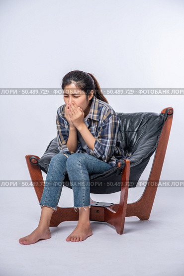 A woman who is uncomfortable and sits on a chair. Стоковое фото, агентство Ingram Publishing / Фотобанк Лори
