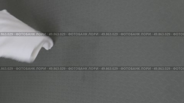 A woman's hand wipes water drops from a black rug with a white cloth. Стоковое видео, видеограф Катерина Белякина / Фотобанк Лори