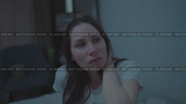A young adult woman sits on a couch in the middle of the night, nervously twirling her hair. Panic attacks and mental health. Стоковое видео, видеограф Денис Кебедов / Фотобанк Лори
